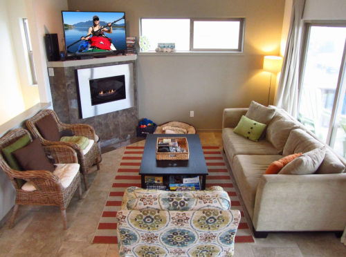 Cozy living room with a fireplace, TV, and comfortable seating, featuring a rug and decorative pillows.