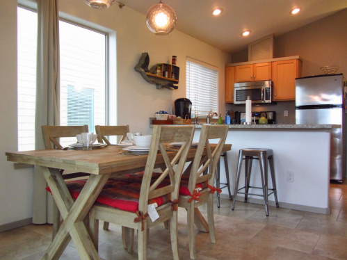 A modern kitchen and dining area featuring a wooden table, chairs, and stainless steel appliances.