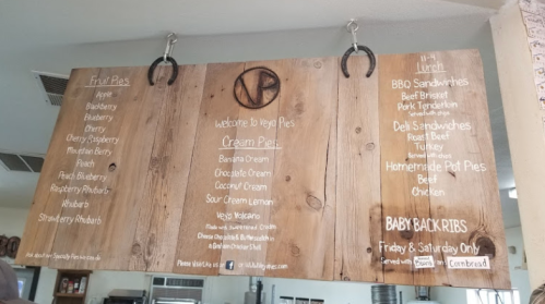 Menu board featuring fruit pies, cream pies, lunch options, and baby back ribs at a restaurant.