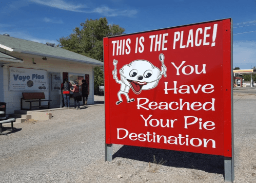 A bright red sign reading "This is the Place! You Have Reached Your Pie Destination" with a cartoon pie character.