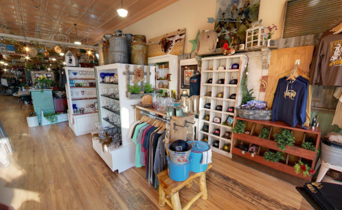 A cozy retail space featuring shelves of merchandise, clothing, and decor with rustic accents and wooden flooring.