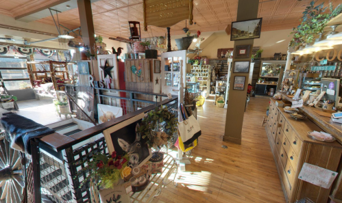 A cozy, eclectic shop interior filled with various decor items, furniture, and unique displays. Warm wooden floors and bright lighting.