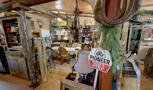 A cozy vintage shop filled with rustic decor, furniture, and unique items, featuring a prominent "Pioneer 3963" sign.