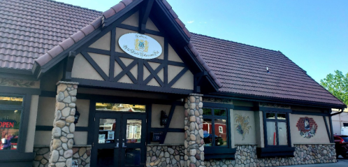 A charming building with a stone facade and a sloped roof, featuring a sign and large windows.