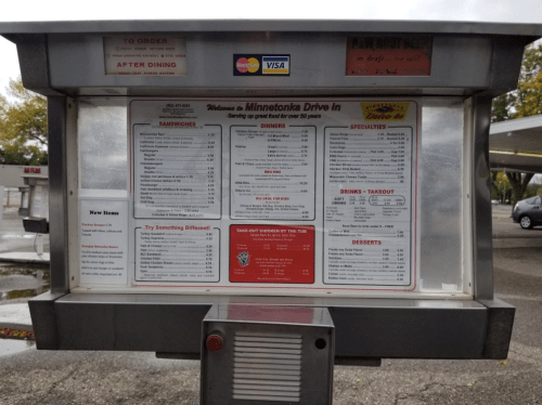 Menu board at Minnetonka Drive-In featuring sandwiches, dinners, drinks, and desserts with prices listed.