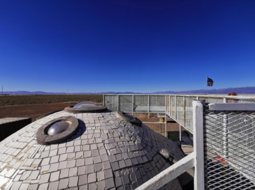 A rooftop view of a dome structure with a clear blue sky and distant mountains in the background.