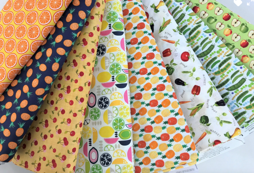 A collection of colorful patterned fabrics featuring fruits and vegetables in various designs.
