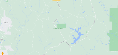 Map showing Gibbs Gardens, surrounded by green areas and water features, with nearby roads and landmarks.