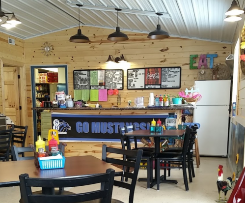 Cozy diner interior with wooden walls, tables, and a counter displaying a "Go Mustangs" banner and condiments.