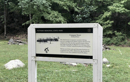 Sign at Putnam Memorial State Park detailing Company Street and its historical significance, surrounded by trees.