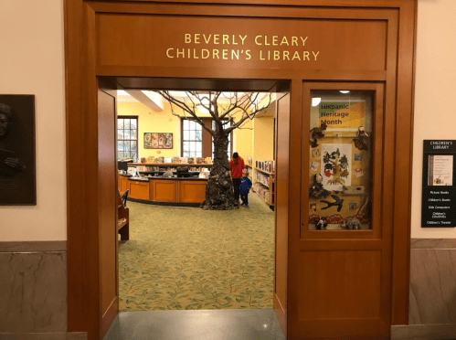 Entrance to Beverly Cleary Children's Library, featuring a tree sculpture and a colorful, inviting interior.