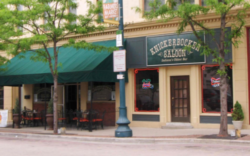 Exterior of Knickerbocker Saloon, Indiana's oldest bar, featuring green awnings and red neon lights.