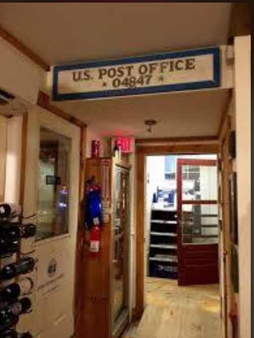 Interior view of a U.S. Post Office entrance, featuring a sign and wooden decor.