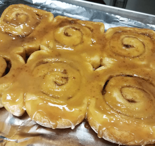 A tray of freshly baked cinnamon rolls topped with a glossy caramel glaze.