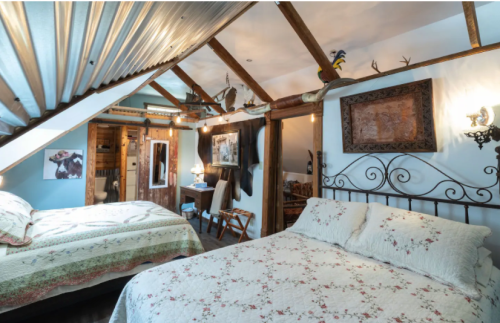Cozy bedroom with two beds, rustic decor, wooden beams, and a warm, inviting atmosphere.