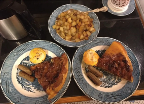 A breakfast spread featuring two plates with sausage, eggs, and a slice of pie, alongside a bowl of diced potatoes.