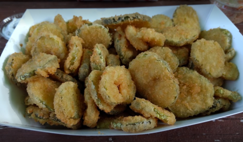 A tray filled with golden-brown, crispy fried pickles.