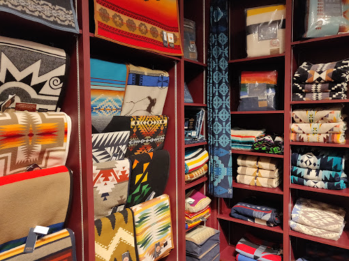 A display of colorful blankets and textiles arranged on shelves, featuring various patterns and designs.