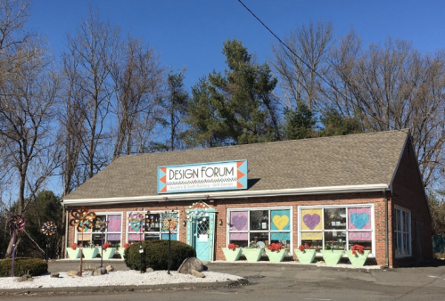 A colorful storefront of "Design Forum" with decorative windows and a clear blue sky in the background.