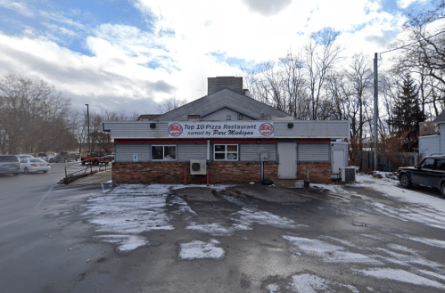 A small pizza restaurant with a sign reading "Top 10 Pizza Restaurant" and a snowy parking lot.