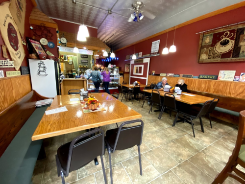 Cozy café interior with wooden tables, chairs, and a counter; patrons enjoying their time in a warm atmosphere.