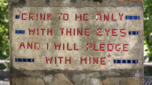 A stone wall with a quote carved in red letters: "Drink to me only with thine eyes and I will pledge with mine."
