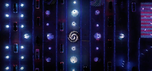 Aerial view of a vibrant, illuminated display with swirling patterns and colorful lights against a dark background.