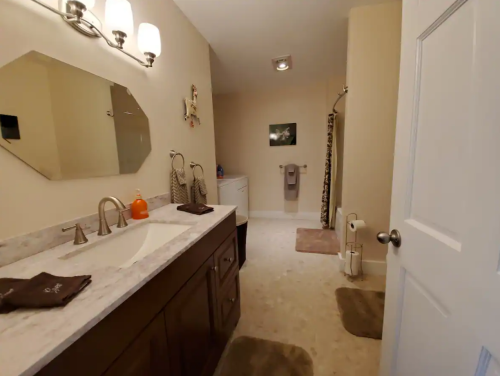 A spacious bathroom featuring a double sink vanity, shower, and neutral decor with towels and rugs.