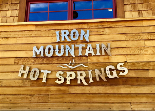 Sign on a wooden wall reading "Iron Mountain Hot Springs" with decorative lettering.