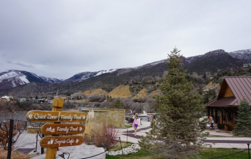 A scenic view of mountains with a signpost indicating areas like Quiet Zone and Family Pool, near a café.