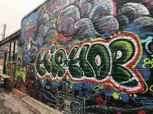 Colorful graffiti on a brick wall featuring the word "LISHTOR" with vibrant designs and patterns surrounding it.