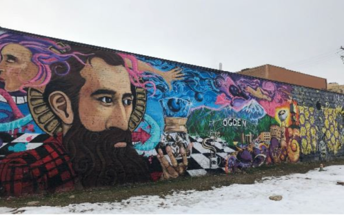Colorful mural featuring a bearded man, abstract designs, and vibrant scenes against a snowy backdrop.