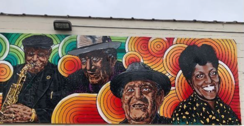 Colorful mural featuring four musicians, including a saxophonist, with vibrant swirls in the background.