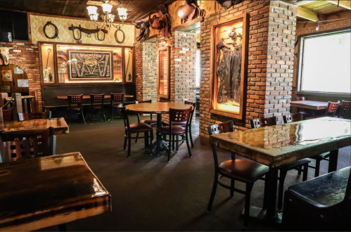 Cozy restaurant interior with wooden tables, brick walls, and rustic decor, featuring empty seating and warm lighting.