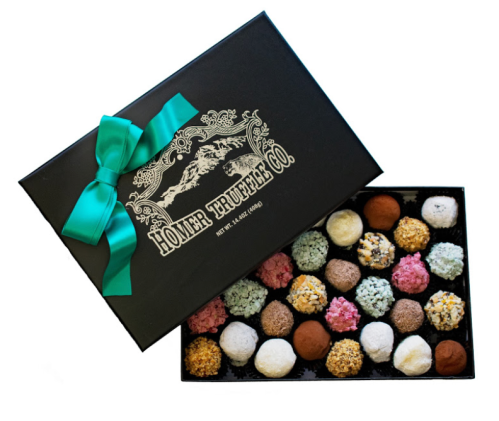 A black box of assorted truffles with a teal ribbon, featuring various colorful chocolate confections inside.