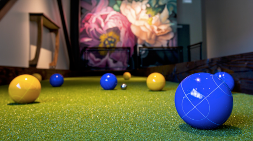 Colorful balls on a green turf surface, with a vibrant floral mural in the background.