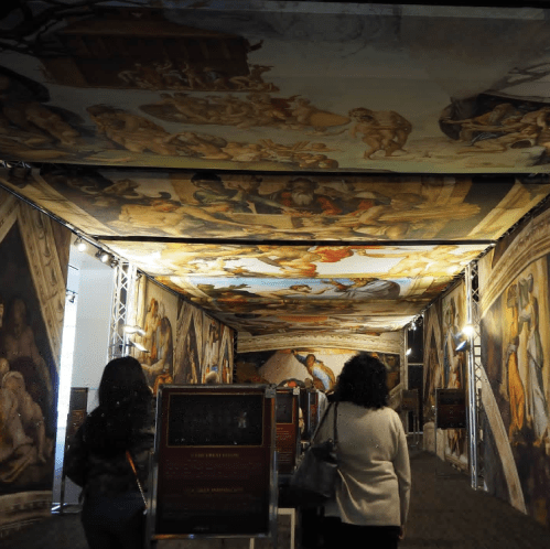 Visitors walk through an exhibition featuring ceiling artwork inspired by Michelangelo's Sistine Chapel.