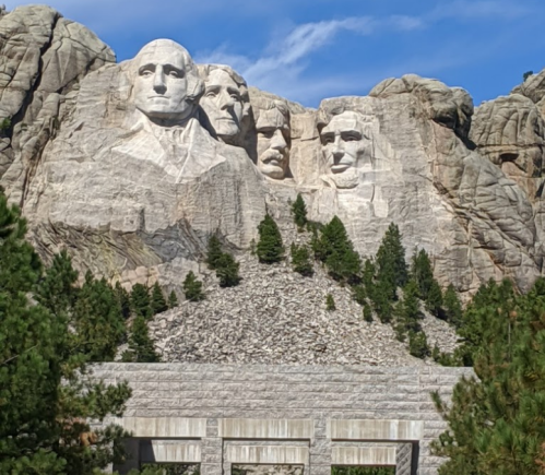 Mount Rushmore featuring the carved faces of four U.S. presidents against a blue sky and green trees.