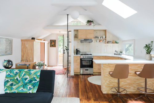 Bright, modern kitchen and living area with wooden accents, a sofa, and large windows for natural light.