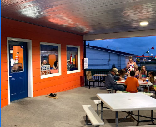 A group of people dining outside a brightly colored building with a blue door, enjoying food and conversation.