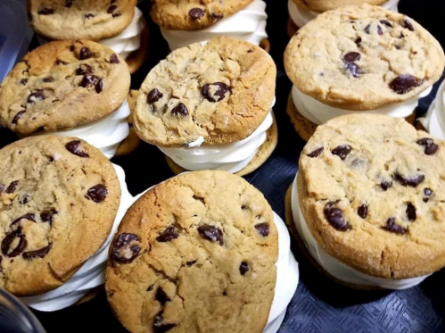 A close-up of chocolate chip cookie sandwiches filled with creamy white frosting.