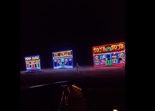 Colorful holiday light displays featuring a toy store and an ice cream shop against a dark night sky.