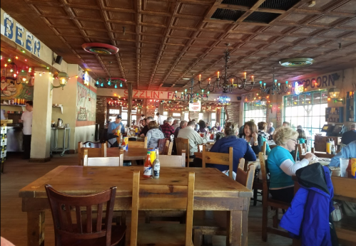A bustling restaurant interior with colorful decor, wooden tables, and diners enjoying their meals.