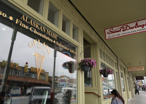 Storefront featuring "Sweet Darlings" sign, gelato display, and flower baskets in a charming Alaskan setting.