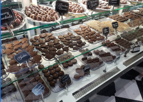 A display case filled with various chocolate confections, including truffles, cherries, and assorted treats.