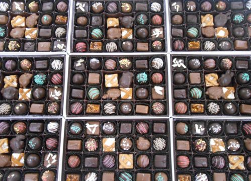 A variety of assorted chocolates arranged in multiple boxes, featuring different shapes, colors, and toppings.