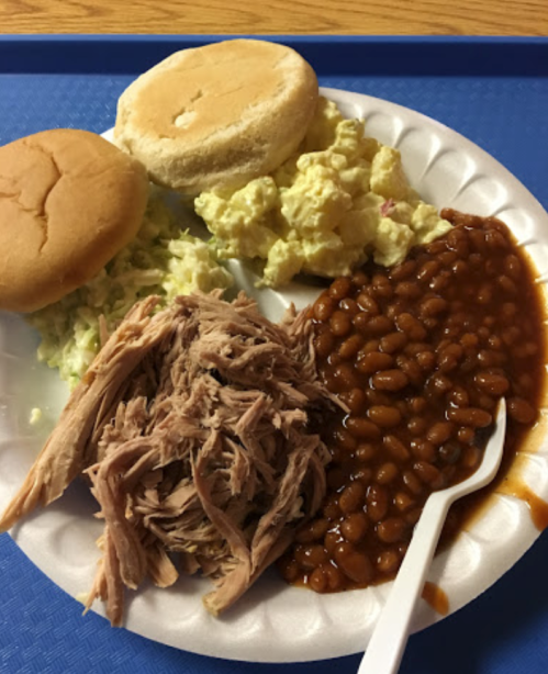 A plate with pulled pork, baked beans, two sandwich buns, and a serving of potato salad.