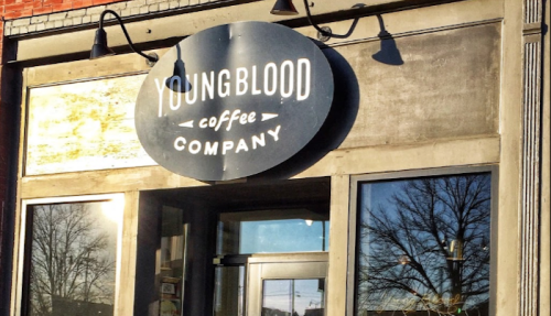Sign for Youngblood Coffee Company on a storefront, featuring a circular logo and large glass windows.