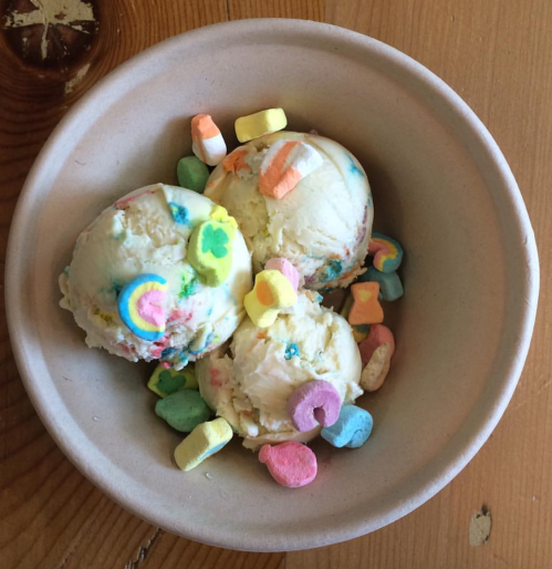 A bowl of three scoops of ice cream topped with colorful marshmallows and sprinkles.