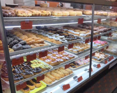 A display case filled with a variety of colorful donuts, including glazed, chocolate, and sprinkled options.